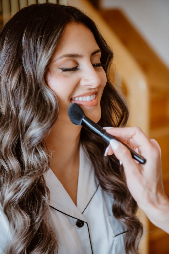 bride smiling getting her wedding makeup done 