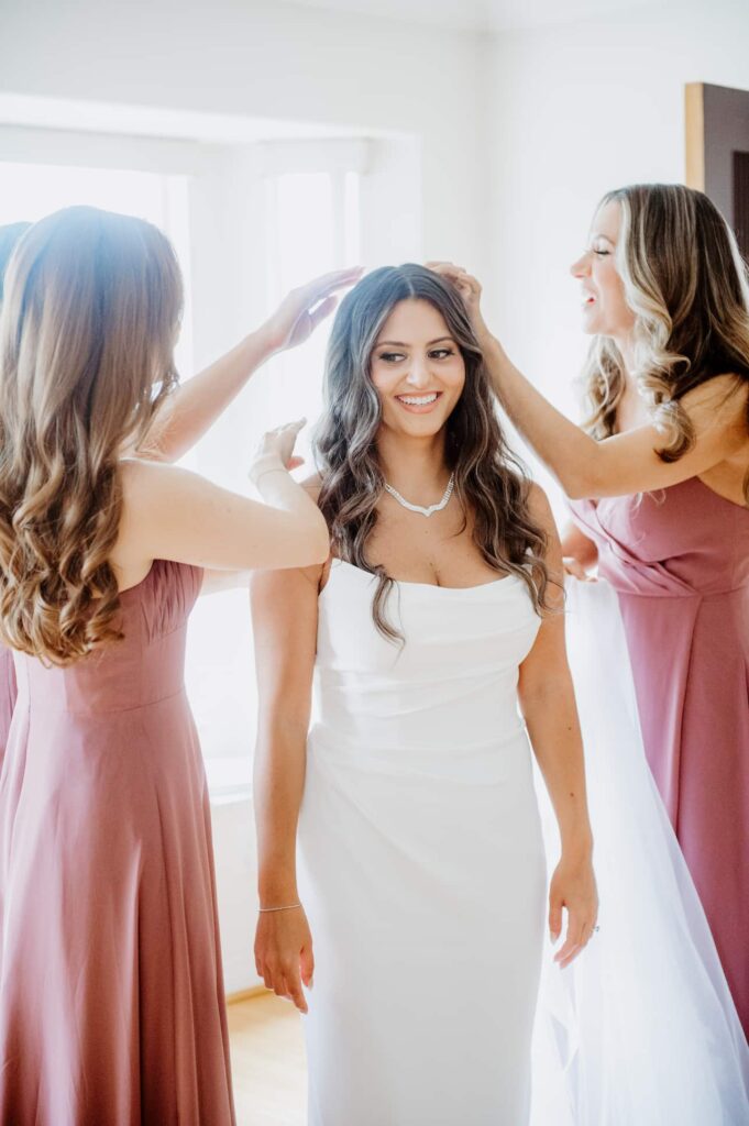 bridesmaids helping the bride getting ready with her bridal makeup look